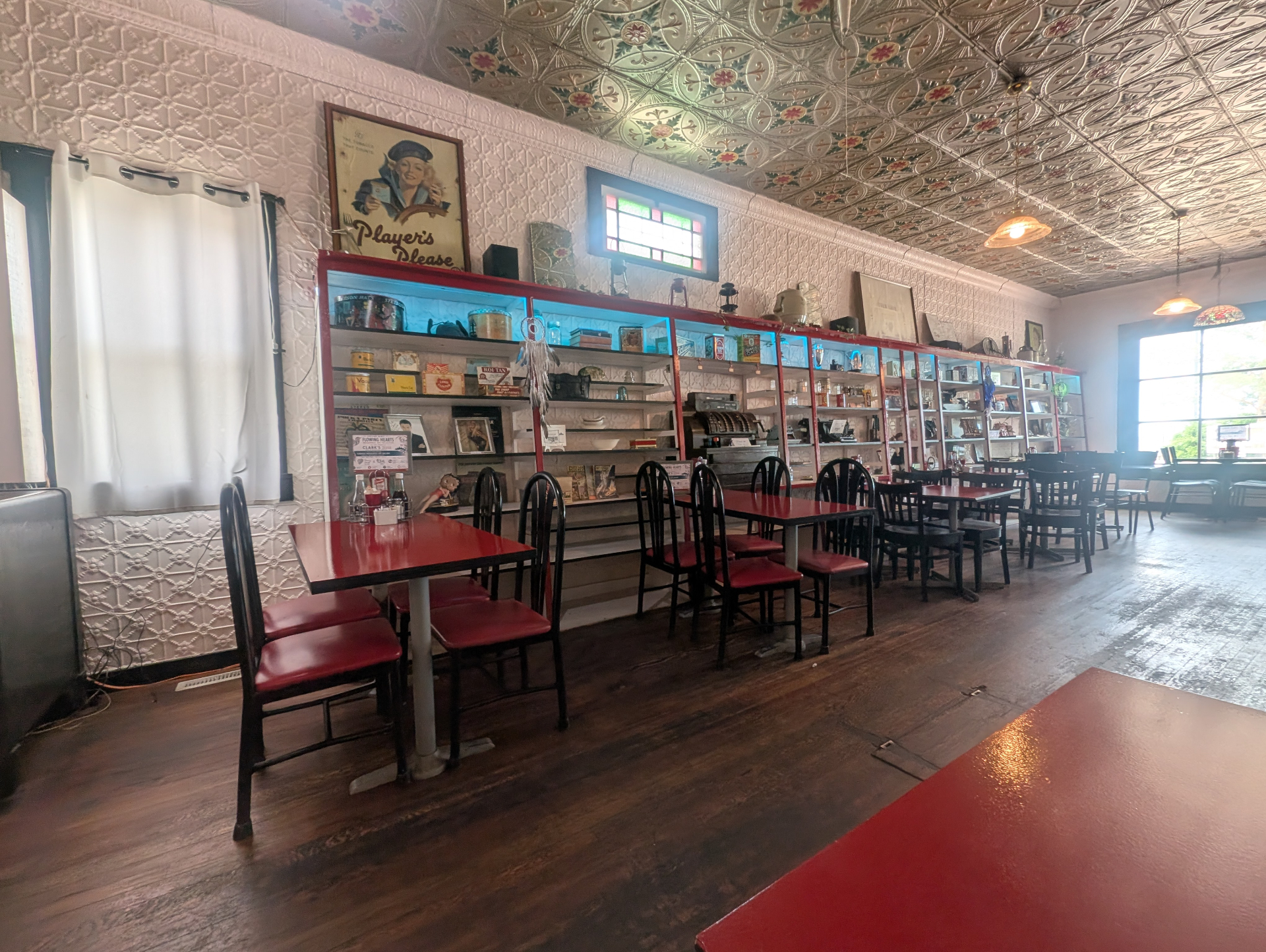 Clark's dining room with red tables, tin ceiling, and antique display shelves